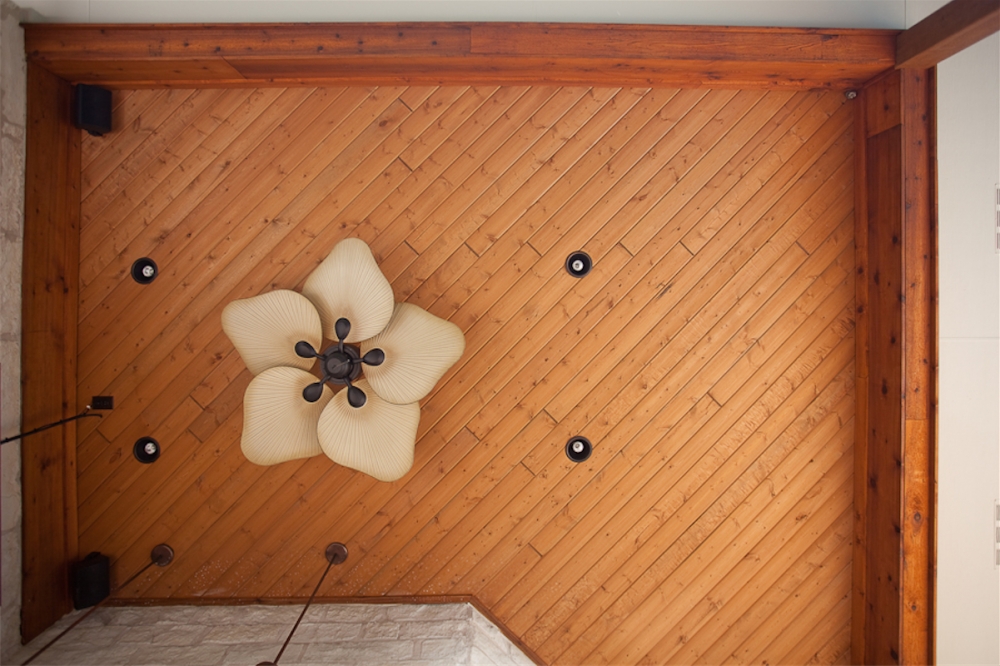 Outdoor kitchen ceiling with recessed lighting fan and angled tongue and groove stained cedar